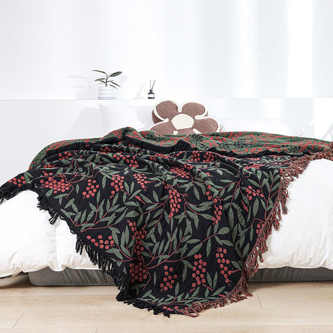 Stylish berry-themed throw blanket with tassels spread over white bed