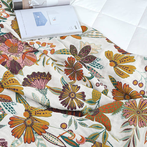 Open book resting on beige floral sofa throw blanket in soft lighting.