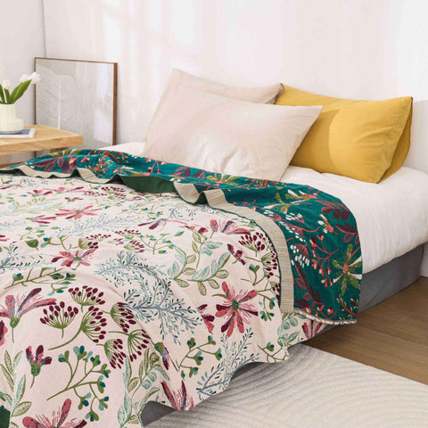 Floral cotton summer gauze blanket styled on queen bed with decorative pillows