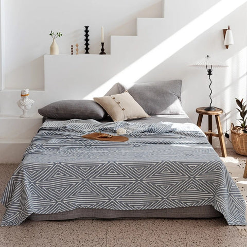 Blue geometric striped cotton blanket displayed on bed