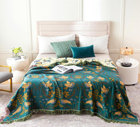 Scandinavian style reversible throw blanket in teal and mustard with botanical pattern spread on a modern bed in a bright bedroom.