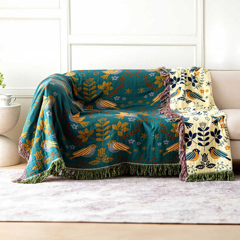 Cozy Scandinest reversible throw blanket with bird and floral patterns draped over a beige sofa in a modern living room