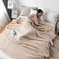 Woman relaxing with pink waffle cotton summer blanket on bed