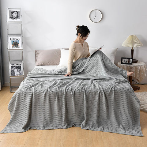 Woman relaxing with pink waffle cotton summer blanket on bed