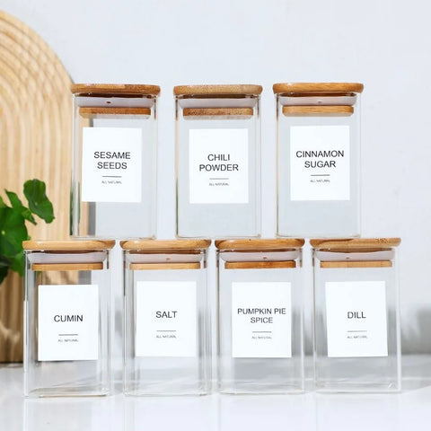 Set of 12 glass spice containers with bamboo lids and matching minimalist labels.

