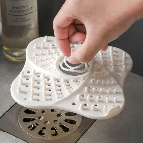 Hand placing a white silicone drain cover over a sink drain.