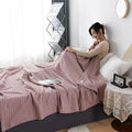 Woman relaxing with pink waffle cotton summer blanket on bed