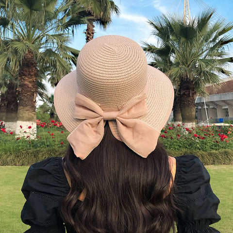 Woman wearing khaki straw sun hat with bow detail