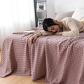 Woman relaxing with pink waffle cotton summer blanket on bed