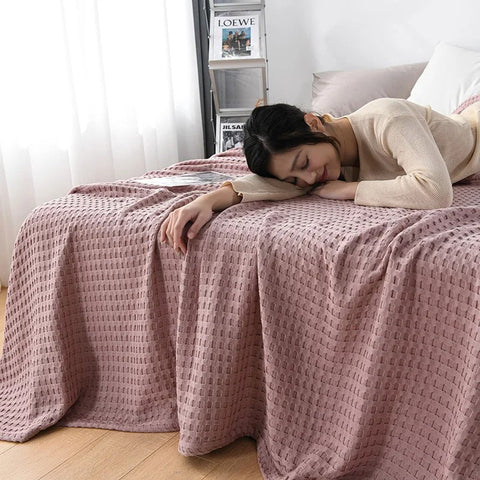 Woman relaxing with pink waffle cotton summer blanket on bed