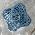 Blue drain hair catcher placed in soapy shower floor