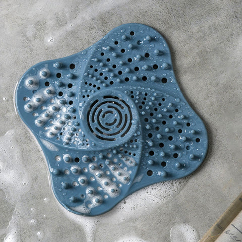 Blue drain hair catcher placed in soapy shower floor