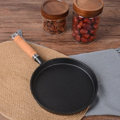 Cast iron skillet with wooden handle and blue cloth underneath