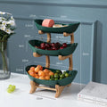 Three-tiered fruit basket with measurements on a white surface with a blue wall background.
