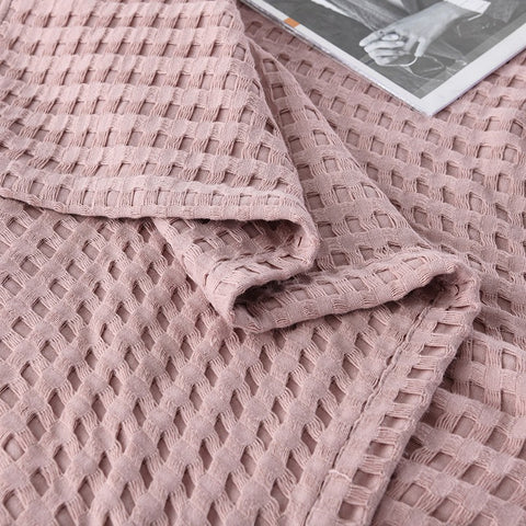 Woman relaxing with pink waffle cotton summer blanket on bed