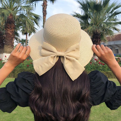 Woman wearing khaki straw sun hat with bow detail