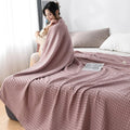 Woman relaxing with pink waffle cotton summer blanket on bed