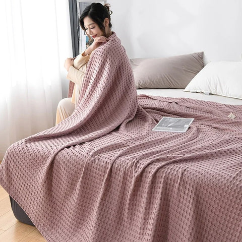 Woman relaxing with pink waffle cotton summer blanket on bed