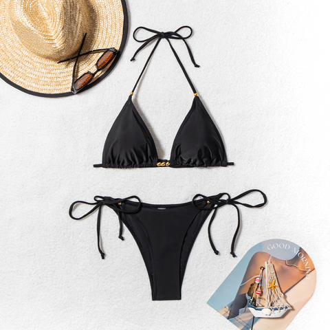 Black bikini set with gold bead accents – flat lay with sunglasses and seashells