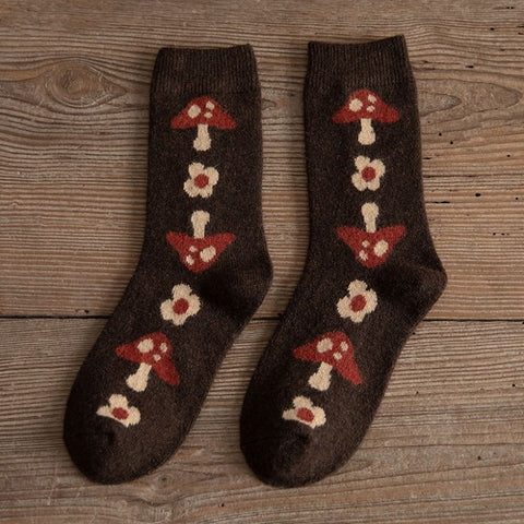 A pair of Yuki Retro Wool Socks with a geometric pattern in brown, red, and beige colors, displayed on a wooden surface.