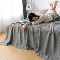 Woman relaxing with pink waffle cotton summer blanket on bed