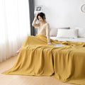 Woman relaxing with pink waffle cotton summer blanket on bed