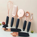 Set of rose gold and black kitchen utensils on a light background