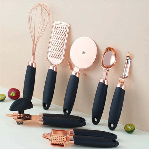 Set of rose gold and black kitchen utensils on a light background
