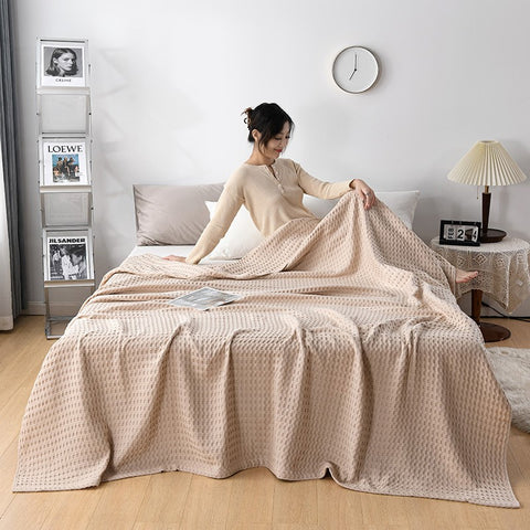 Woman relaxing with pink waffle cotton summer blanket on bed