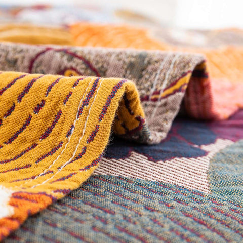 Close-up texture and stitching detail of Persimmon Bloom cotton blanket fabric