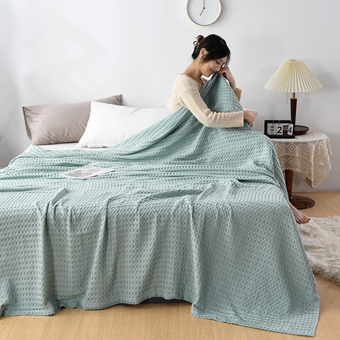 Woman relaxing with pink waffle cotton summer blanket on bed