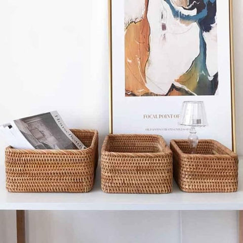 Three woven baskets on a shelf with a piece of abstract art in the background.