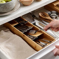 Hand placing fork in bamboo drawer organizer with utensils neatly stored

