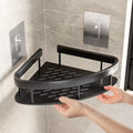 Black corner shower caddy held by a hand against a tiled bathroom wall.
