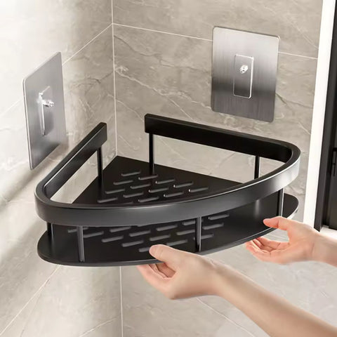 Black corner shower caddy held by a hand against a tiled bathroom wall.