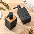 Black soap dispenser and pump on a wooden surface with greenery and towels in the background
