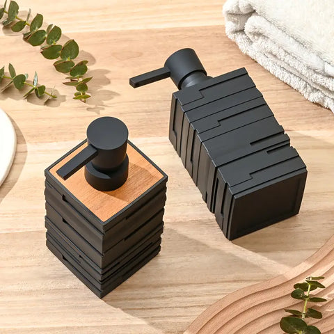 Black soap dispenser and pump on a wooden surface with greenery and towels in the background