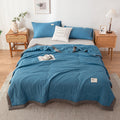 Blue bedding set quilt summer on a bed in a bedroom with wooden nightstands and decor.