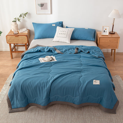 Blue bedding set quilt summer on a bed in a bedroom with wooden nightstands and decor.