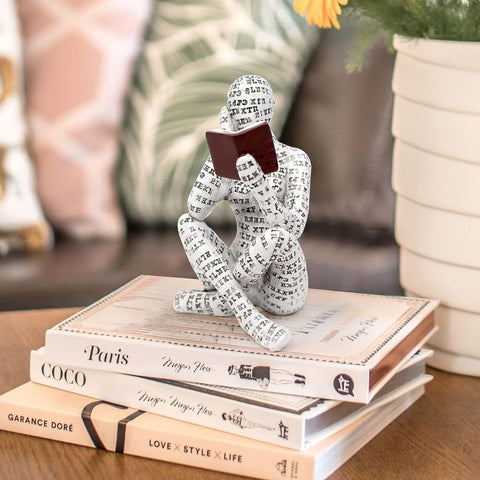 Decorative figure made of paper or fabric sitting on books with a blurred background
