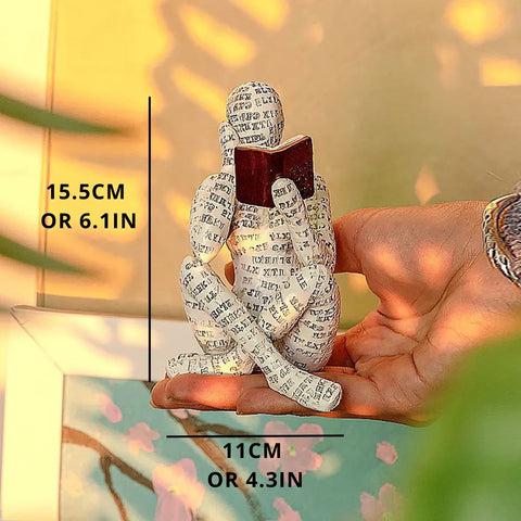 Decorative figure of a person reading a book held by a hand, with measurements indicated.