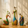 Colorful ceramic figurines on a wooden surface with a soft curtain background