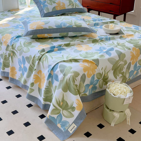 Floral patterned bedspread on a bed with a decorative vase of flowers on a checkered floor.