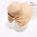 Woman wearing khaki straw sun hat with bow detail
