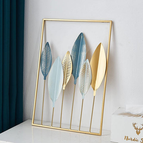 Decorative wall art with gold, blue, and white leaf shapes in a gold frame.