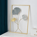 Decorative wall art with gold and gray leaf design on a white surface.