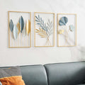 Three framed leaf art pieces on a wall above a sofa.