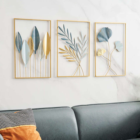 Three framed leaf art pieces on a wall above a sofa.
