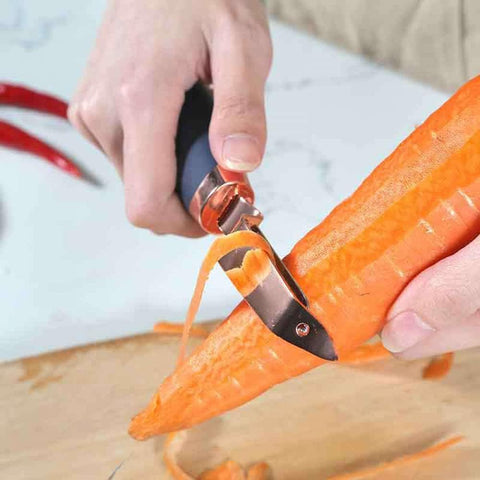 Person using a carrot peeler to peel a carrot on a wooden cutting board.