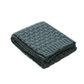 Folded dark green textured blanket on a white background